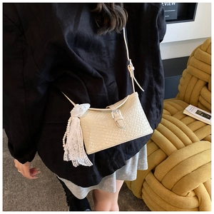 Détail du sac seau en cuir tressé beige avec nœud en dentelle et chaîne perle