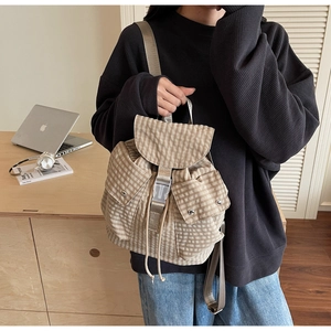 Detail of plaid canvas backpack featuring a drawstring closure and buckle fastenings