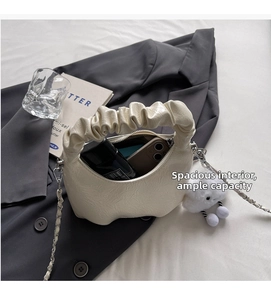Detail showing the spacious interior of the beige pleated cloud bag with daily items