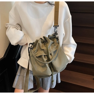 Detail of army green nylon bucket bag with adjustable straps and drawstring closure