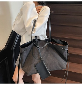 Detailed macro view of large black tote bag with leather straps and detachable pouch