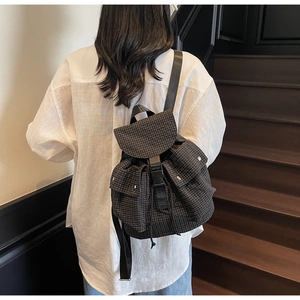 Detail of checkered canvas backpack with buckle closure and drawstring on model