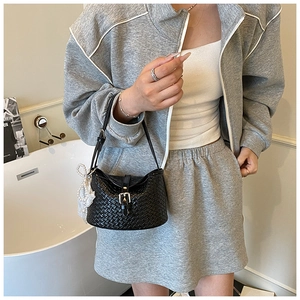 Détail d'un sac seau tressé noir avec boucle argentée et nœud en perles blanches