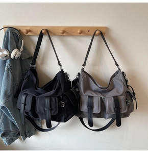 Detail of workwear style tote bags with multi-pockets and leather straps on wooden rack