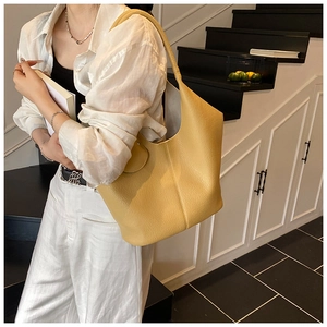 Detailed view of yellow lychee texture leather tote bag worn over the shoulder in daily use