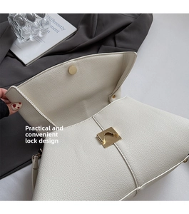 Close-up of off-white lychee grain leather handbag with golden metal square buckle lock