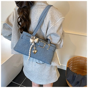 Detail of blue denim bucket bag featuring silver bow charms and striped scarf accent