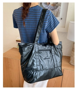 Détail d'un grand sac cabas noir matelassé avec poche zippée et logo brodé élégant