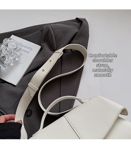 Detail of adjustable wide shoulder strap and lychee grain texture on white leather bag