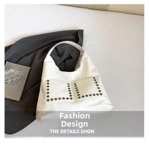 Detail of white matte leather tote bag featuring rivet studs and large front pockets