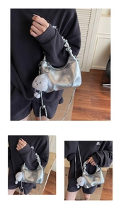 Close-up of metallic silver hobo bag featuring pleated handle and white cloud charm