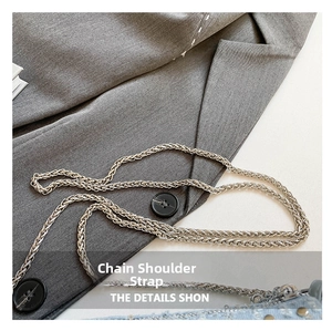 Close-up of silver metal chain strap on light blue denim bag with studs and sequins