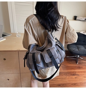 Close-up of grey multi-pocket nylon crossbody bag with adjustable black strap