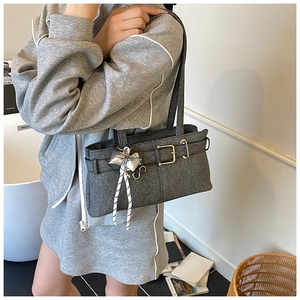 Detailed macro of grey denim bucket bag featuring a silver bow charm and metal buckle strap