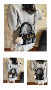 Close-up of black pleated cloud bag with silver chain and white fluffy charm detail