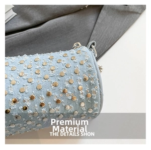 Macro detail of light blue denim barrel bag featuring golden metal studs and chain strap