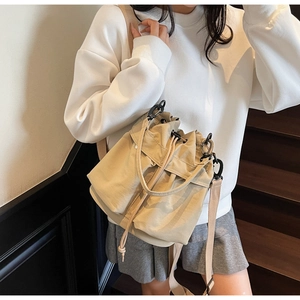 Dettaglio della borsa a secchiello beige con coulisse, tasche esterne e tracolla regolabile