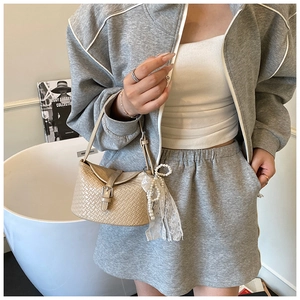 Détail du sac seau tissé beige avec charm nœud en dentelle perlée et boucle argent