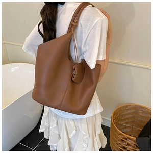 Detail shot of brown lychee grain leather tote bag with circular pendant accessory