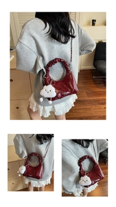 Detail of burgundy ruched moon bag with plush cloud charm and silver chain strap