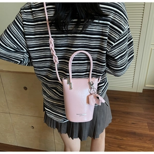 Pink leather bucket bag with braided strap and elephant charm worn by a model