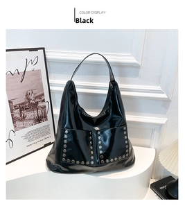 Detail of black glossy hobo bag with dual front pockets and silver hexagonal studs