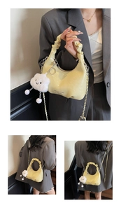 Detail of yellow pleated crescent bag with chain strap and cloud plush charm