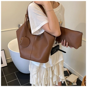 Detail of caramel brown lychee texture leather tote bag with matching small clutch pouch