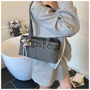 Detail of dark grey denim bucket bag featuring silver buckle and star pendant accessory