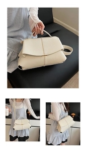 Detail of cream leather handbag showing lychee texture and adjustable strap in use
