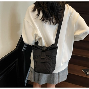 Détail d'un sac bandoulière en nylon noir avec fermeture roll-top et sangle sur modèle