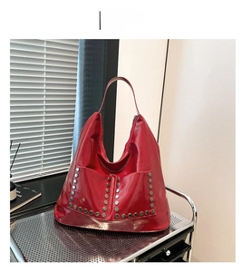 Close-up of red tote bag featuring silver hexagonal stud accents and glossy leather finish