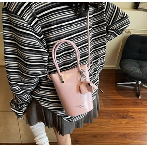 Pink bucket bag with a cute elephant charm shown on a model for a stylish lifestyle look