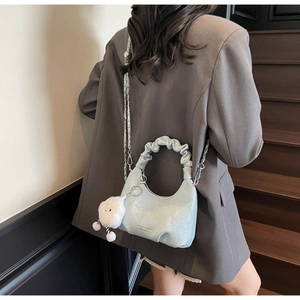 Detail of light blue glossy cloud bag featuring ruched handle and plush charm