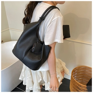 Detail of black pebbled leather tote bag with knotted shoulder strap and round coin purse