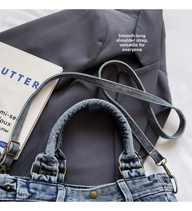 Dettaglio dei manici in denim a pieghe e fibbie in rame vintage sulla borsa blu