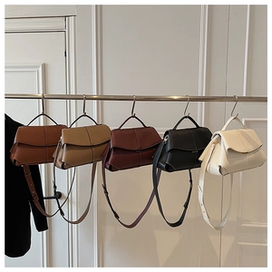 Various colors of geometric patchwork leather shoulder bags displayed on a metal rack