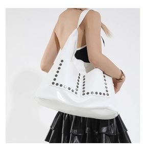 Detail of white hobo shoulder bag with silver hexagonal rivets on glossy leather surface