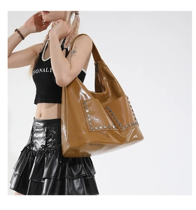 Detail of glossy caramel tote bag with silver hexagonal rivets and sleek pocket