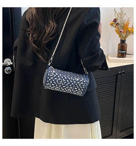 Rear view of a chic navy denim cylindrical crossbody bag with silver studs and chain