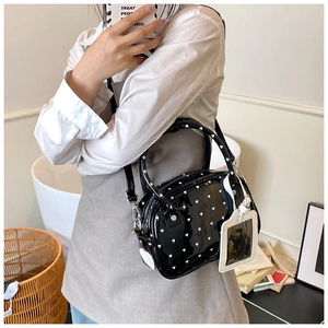 Detail of black glossy handbag with white heart prints and removable card holder charm
