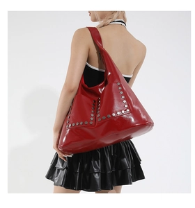 Detail of red patent leather shoulder bag with silver hexagonal rivets and punk style