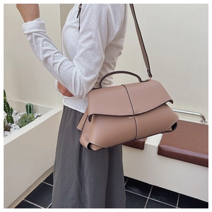 Detail of tan leather shoulder bag featuring white contrast stitching and top handle design