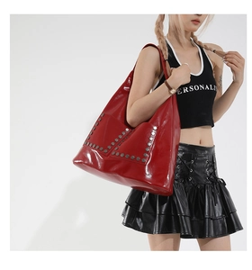 Macro detail of red patent leather tote bag featuring silver hexagonal metal rivets