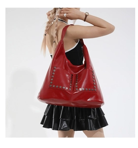 Macro detail of red patent leather tote bag featuring shiny silver hexagonal rivets