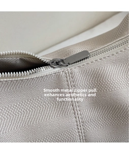 Detailaufnahme des glatten Metallreißverschlusses und des strukturierten Stoffes der Tasche