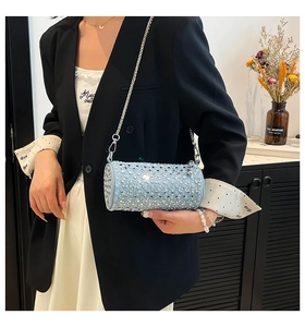 Detail of light blue cylindrical crossbody bag with silver studs and chain strap