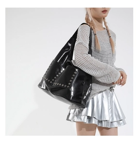 Side view of black large tote bag with silver studs on glossy leather for modern office style
