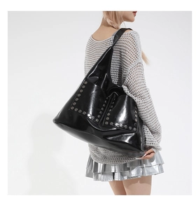 Macro detail of glossy black tote bag featuring silver rivet hardware and dual pockets