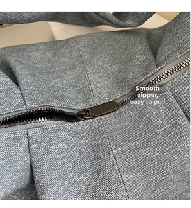 Detailed macro shot of the smooth black metal zipper on blue denim horn bag